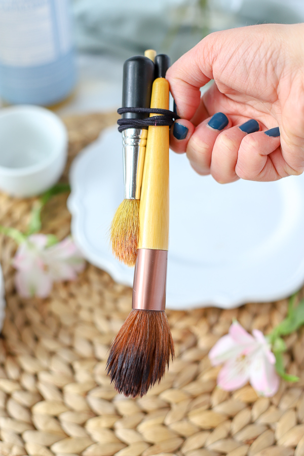 makeup brushes recently cleaned with DIY makeup brush cleaner tied together with a rubber-band and hung to dry