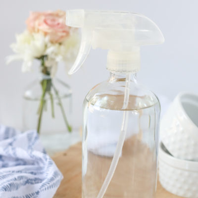 DIY glass cleaner in a glass bottle on a wood cutting board