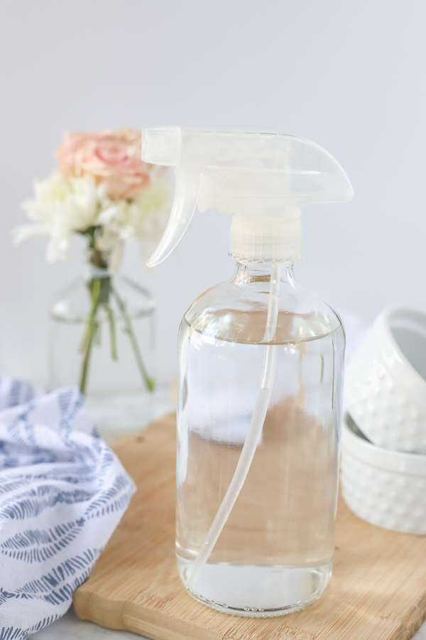 DIY glass cleaner in a glass bottle on a wood cutting board