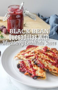 Black bean quesadillas topped with blackberry enchilada sauce on a stone plate with enchilada sauce in jar behind it.