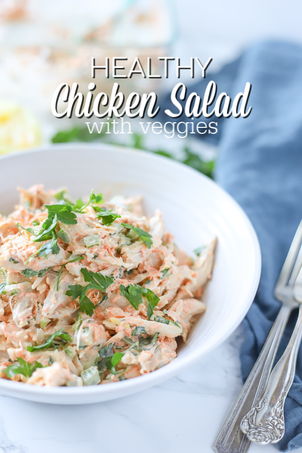 healthy chicken salad in a white bowl on top a blue napkin with antique forks to the right