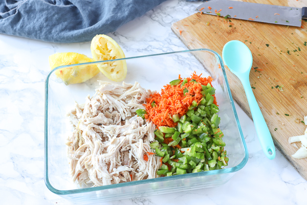 chicken, peppers, and carrots in glass bowl to make healthy chicken salad