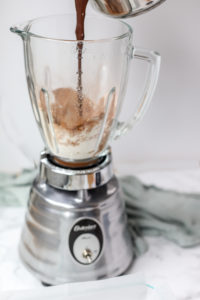 adding melted chocolate to blender to make healthy chocolate brownies