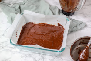 healthy brownie batter poured into a parchment lined baking dish