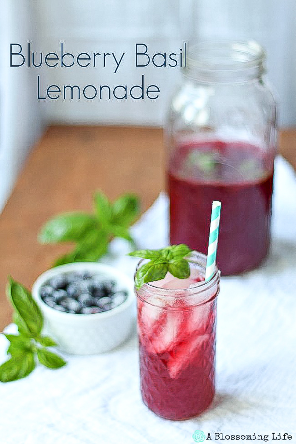 blueberry lemonade with a sprig of basil and a teal straw on a white towel
