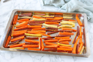 sliced carrots carefully placed onto baking sheet to bake into carrot fries