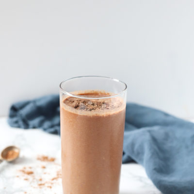 chocolate cauliflower smoothie in a glass cup with chocolate chips and cocoa powder around it