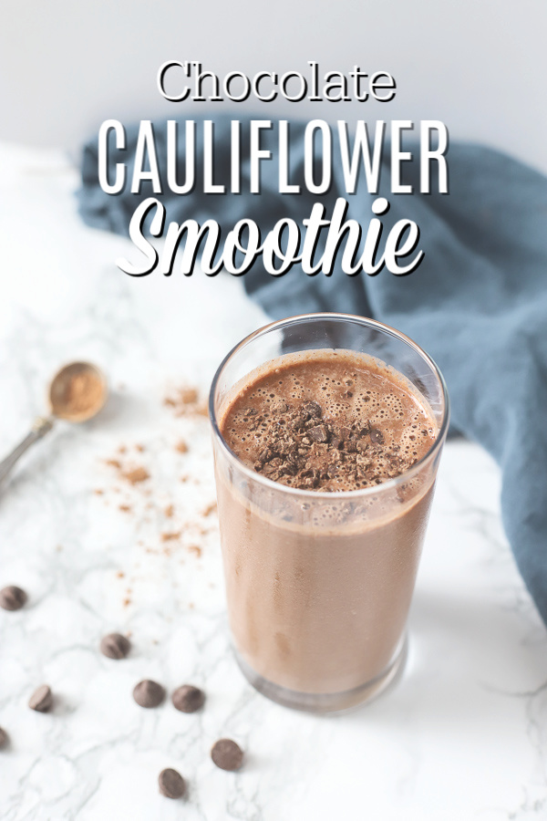 chocolate cauliflower smoothie topped with chocolate shavings in a glass cup with a blue napkin behind it