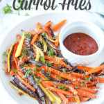 colorful baked carrot fries sprinkled with parsley and cheese on a white plate with ketchup