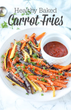 colorful baked carrot fries sprinkled with parsley and cheese on a white plate with ketchup