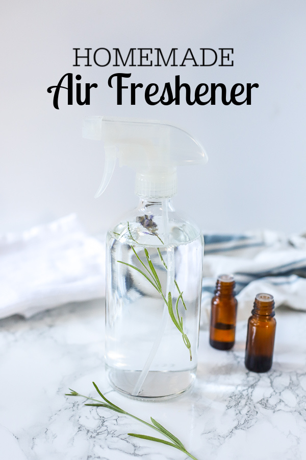 homemade air freshener in a glass spray bottle with lavender inside. Essential oils and a white and blue napkin are behind it