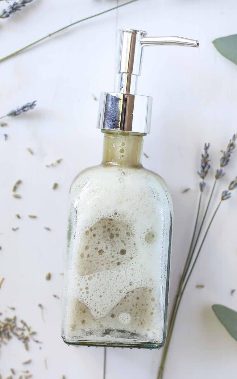 close up of a soap dispenser filled with diy face wash on a white table with dried lavender surrounding the bottle
