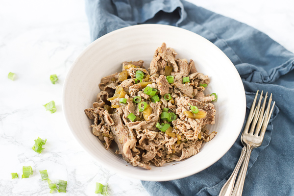 Italian beef recipe in a bowl on top a blue napkin with antique forks