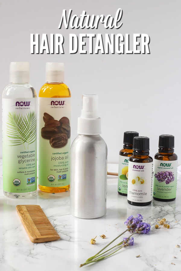 Natural hair detangler in spray bottle with essential oils and other ingredients around