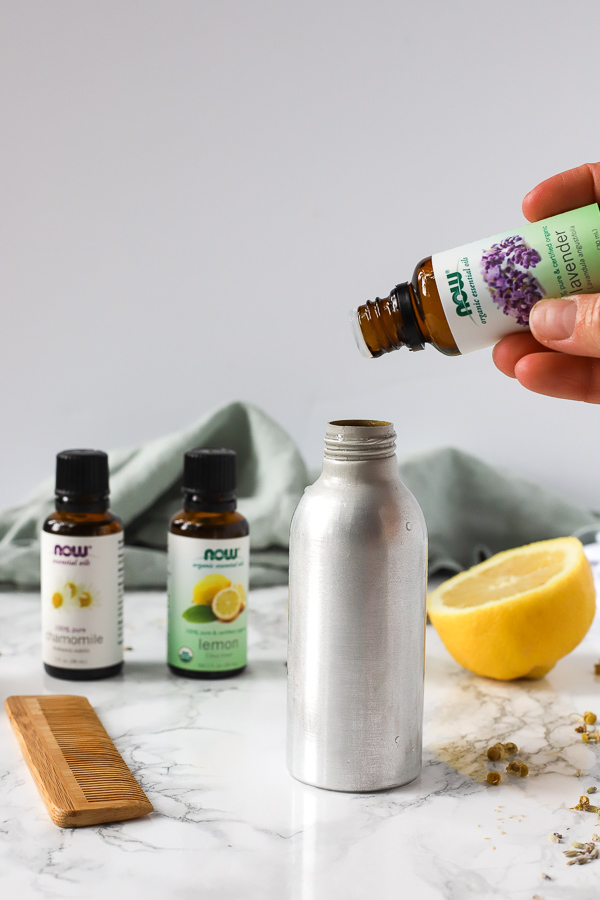 adding essential oils to a metal spray bottle to make homemade natural hair detangler