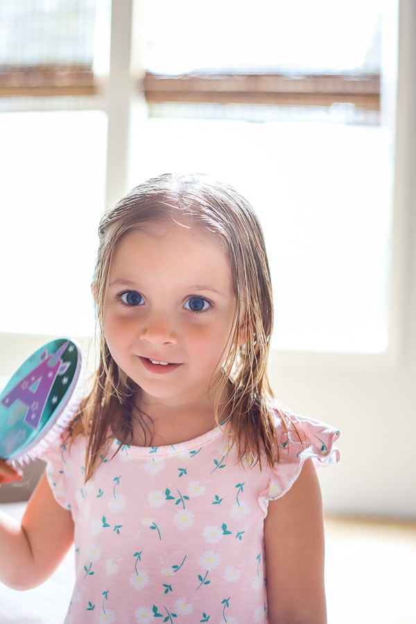 girl brushing wet hair wearing pink dress