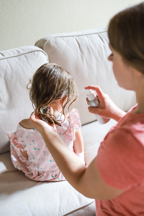 women spraying natural hair detangler on little girl