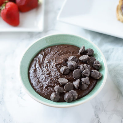 bowl of brownie batter hummus with a plate of strawberries and toast with chocolate hummus behind it