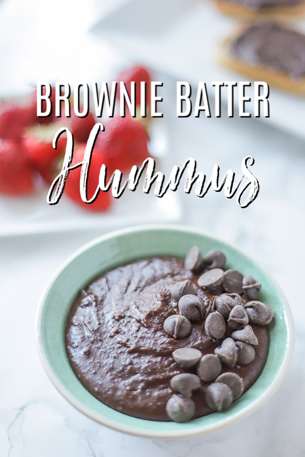 bowl of brownie batter hummus topped with chocolate chips with strawberries behind it