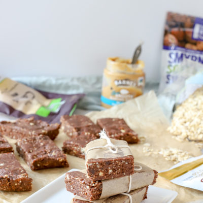 homemade double chocolate energy bars stacked up with more bars and ingredients behind it