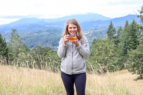 women sipping TeaWell tea with the mountains behind her