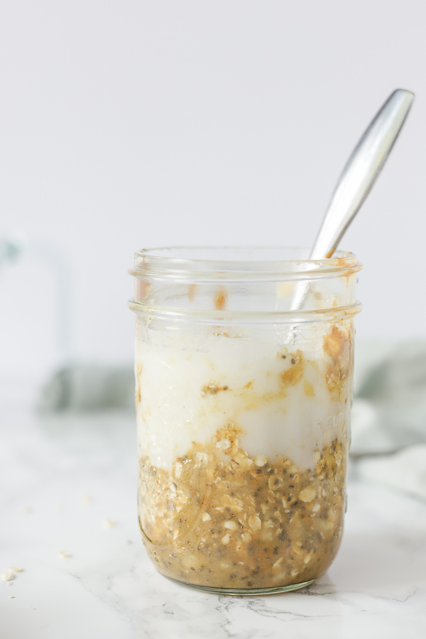milk poured into oatmeal, peanut butter and chia mixture to make overnight oats.