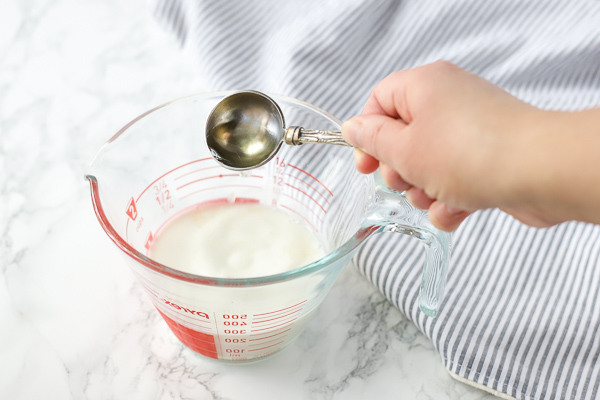 adding vinegar to whole milk in a measuring cup to make homemade buttermilk