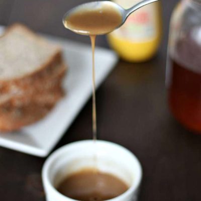 homemade honey mustard sauce in a white dish with a spoon drizzling it