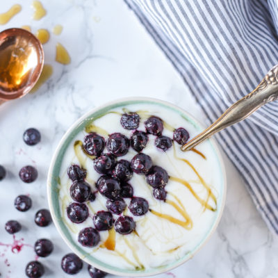 homemade yogurt in a bowl with blueberries and honey