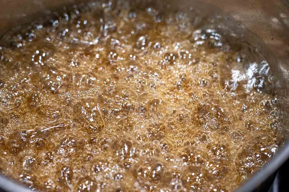 Sugar, maple syrup and water boiling in a saucepan.