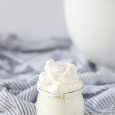 fresh whipped cream on a white and blue stripped towel with a large mixing bowl in the background