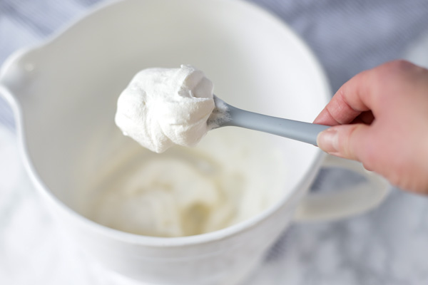 homemade whipped cream on a gray silicon spatula