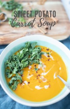 sweet potato and carrot soup with swirls of coconut milk and topped with kale and sprinkled with red peppers