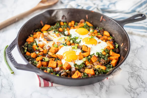 healthy sweet potato hash with kale, sausage and topped with eggs