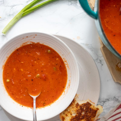 easy tomato soup recipe in a bowl with a dutch oven to the right.
