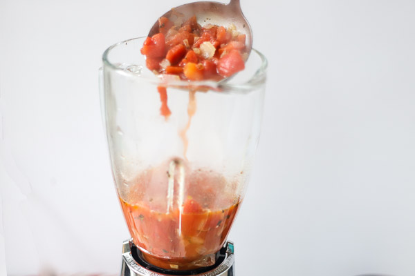tomato soup being ladled into a blender to puree into tomato soup