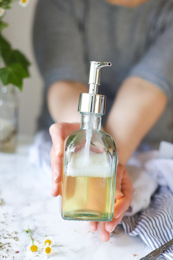 women wearing a green shirt holding out DIY body wash in a soap dispenser