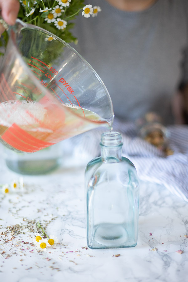 pouring homemade body wash into a glass soap dispenser