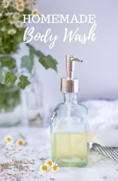 homemade body wash in a glass soap dispenser on a marble countertop with chamomile flowers and dried lavender spread around
