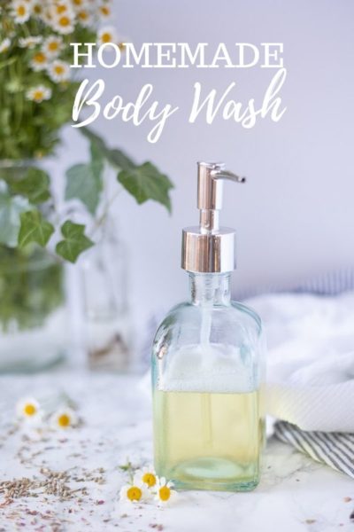 homemade body wash in a glass soap dispenser on a marble countertop with chamomile flowers and dried lavender spread around
