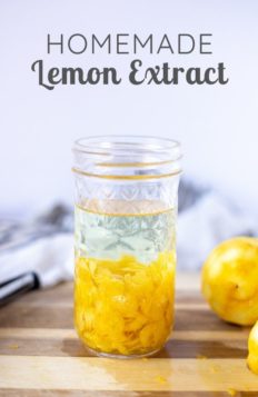 homemade lemon extract in a glass mason jar with lemons around a wood cutting board