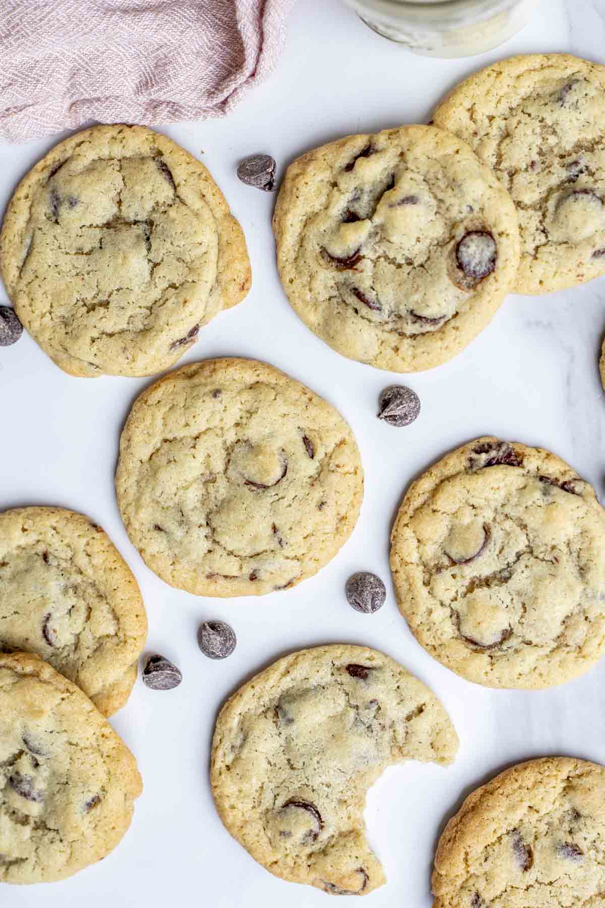 Overhead photo of sourdough chocolate chip cookies on a countertop. One cookie has a bite taken out.