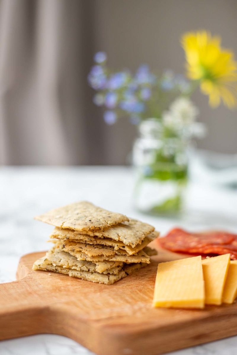 a charcuterie board with homemade sourdough crackers, cheese slices and pepperonis.