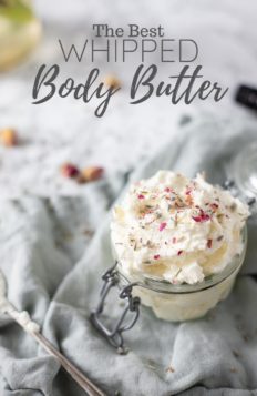 coconut whipped body butter with crushed dried roses on top in a glass jar on top a blue napkin