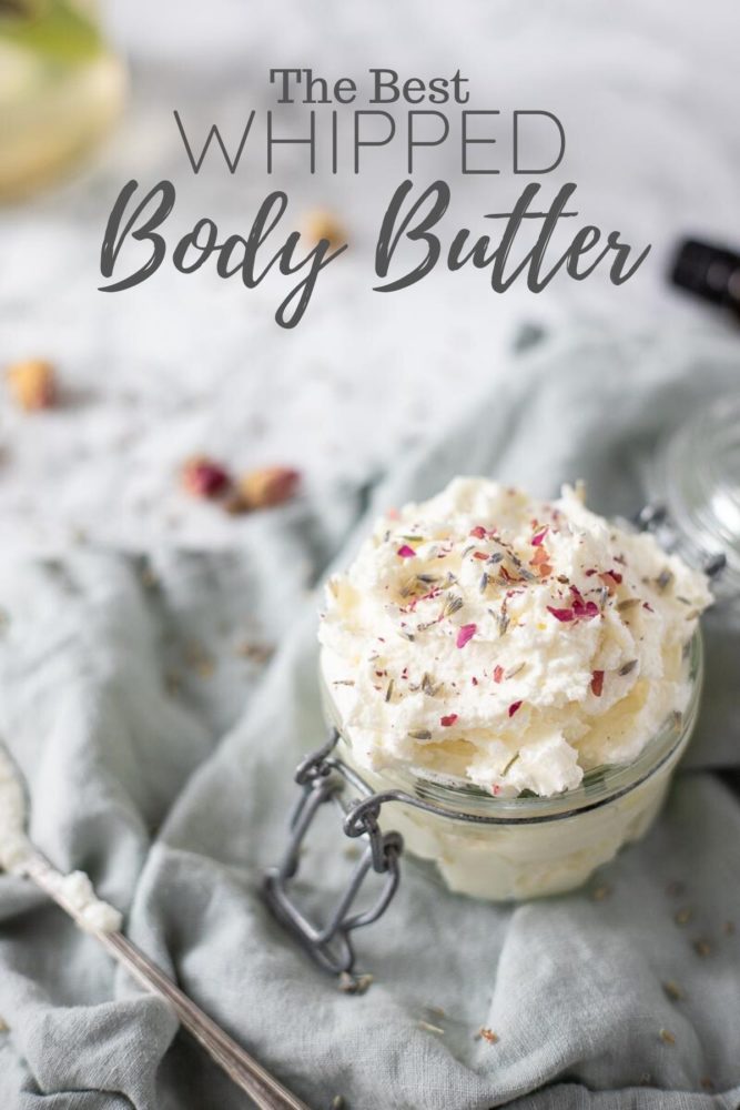 coconut whipped body butter with crushed dried roses on top in a glass jar on top a blue napkin