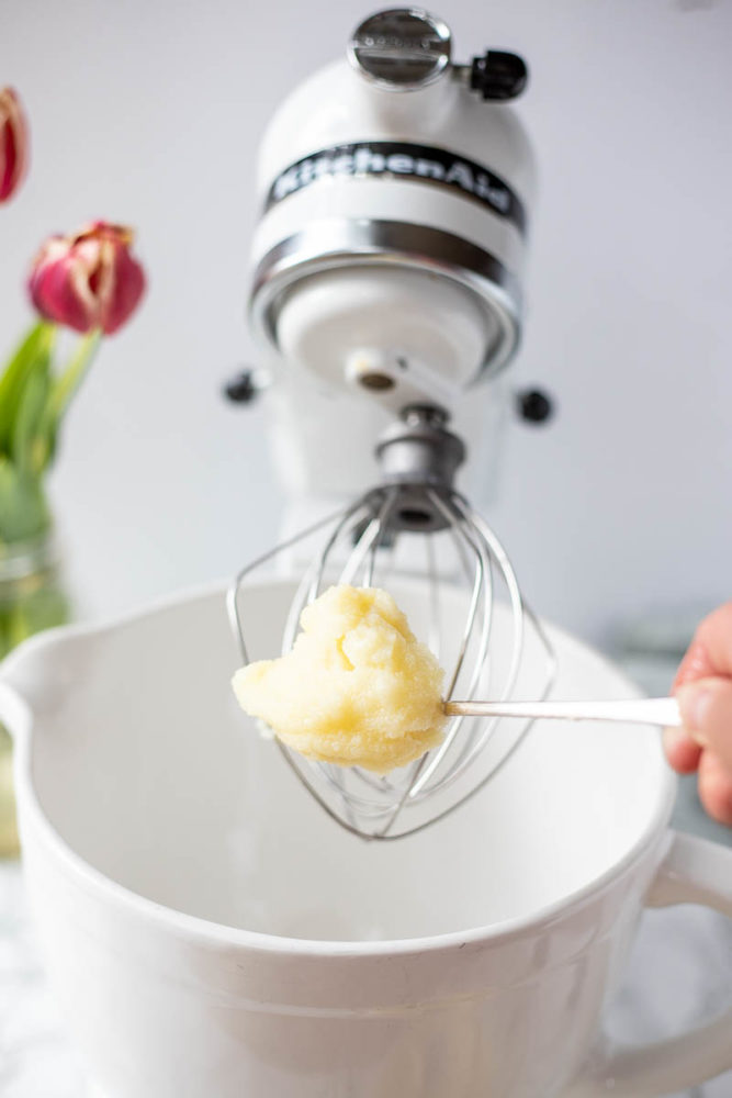 semi-solid body butter in a spoon going into a stand mixer bowl