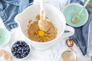 vanilla and eggs being added to wet ingredients in a stand mixer bowl