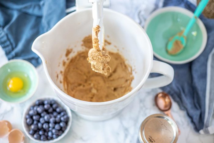 softened butter, sugar, and honey whipped until fluffy in a stand mixer. Blueberries and other ingredients are surrounding the bowl