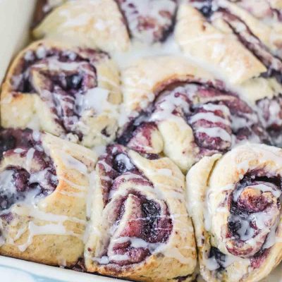 close up of a baking dish of blueberry sourdough sweet rolls with icing