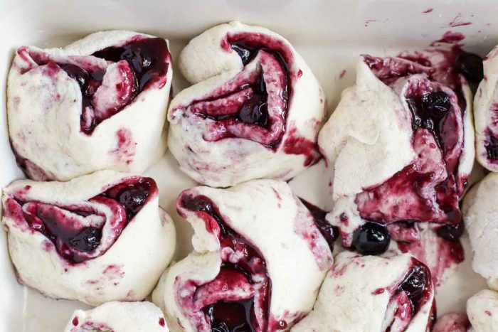 raw blueberry rolls in a baking dish ready for baking